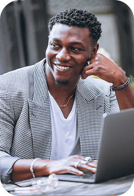 A man smiling at a table with a laptop, representing a testimonial for Mundida Digital Marketing Agency